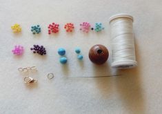 various bead supplies are laid out on the floor next to a spool of thread