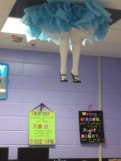 there is a blue and white dress hanging from the ceiling in front of a purple wall