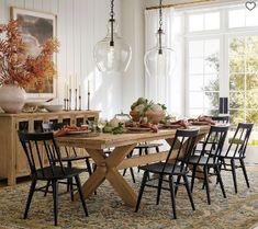 a dining room table and chairs in front of a large window with an area rug on the floor