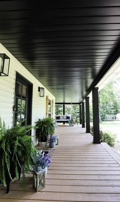 the front porch is covered with plants and potted plants on either side of it