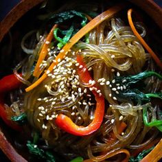 a wooden bowl filled with noodles and vegetables