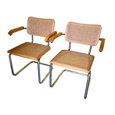 two wooden chairs with metal legs and cane backrests, one is beige the other is light brown