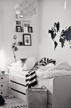 a black and white photo of a bedroom with a world map on the wall above the bed