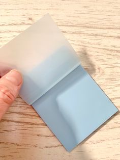 a person holding onto a piece of blue paper