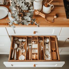 an open drawer with utensils and spoons in it on a kitchen counter