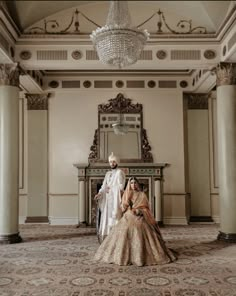 two brides sitting on the floor in front of a chandelier