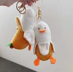 two stuffed animals are hanging from a keychain that is being held by someone's hand