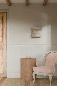 a pink chair sitting in front of a wooden door next to a basket on the floor