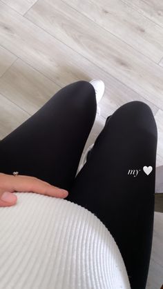 a person wearing black and white leggings sitting on top of a chair with their hands on the legs