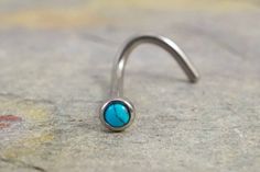 a nose ring with a turquoise stone in it's center on the concrete floor