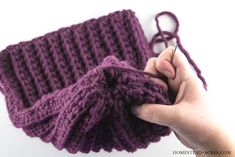 a hand holding a purple knitted object