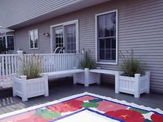 an outdoor deck with potted plants on it and a christmas rug in the foreground