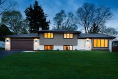 a large house sitting in the middle of a lush green field at night with lights on