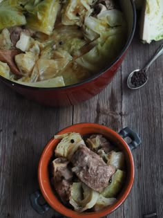 an orange bowl filled with meat and vegetables next to a spoon on a wooden table