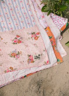 three quilts are laying on the ground next to a potted plant