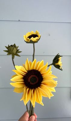 a person holding up a fake sunflower in their hand