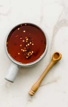 a cup of tea and a wooden spoon on a marble counter top with some spices in it