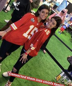 two women in red jerseys posing for a photo at an event with people behind them