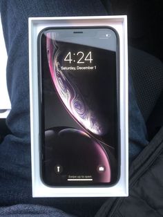 an iphone xr in its box sitting on someone's lap, with the display showing