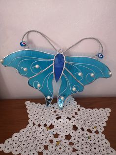 a blue and white butterfly sitting on top of a table next to a doily