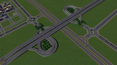 an aerial view of two intersecting roads in the middle of a green area with buildings and trees