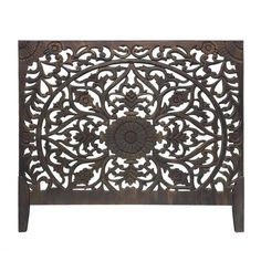 an intricately carved wooden headboard with flowers and leaves on the top, against a white background