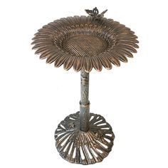 a metal flower shaped vase sitting on top of a table