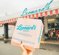 a person holding up a pink bag in front of a store that sells lemonade