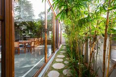 an outdoor dining area with bamboo trees and stone stepping stones on the ground in front of glass doors