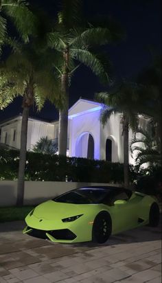 a lime green sports car parked in front of a house at night with palm trees