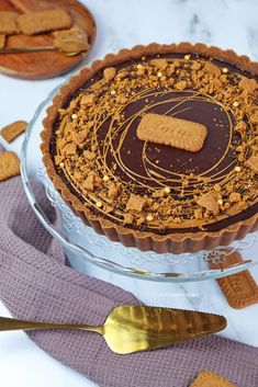 there is a chocolate pie with crackers on the top and spoons next to it