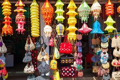 many colorful bags and purses are hanging from the ceiling in front of a store