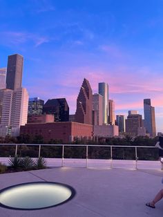 a person sitting on a bench in front of a cityscape at dusk with the sun setting