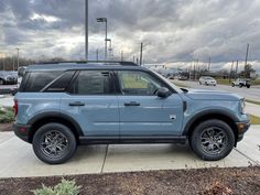 a light blue suv parked on the side of a road next to a parking lot