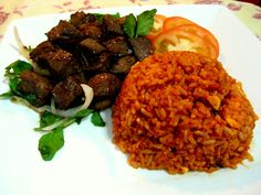 a white plate topped with meat and rice next to tomatoes, lettuce and onions