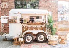 an ice cream truck parked in front of a brick building with plants and wicker chairs