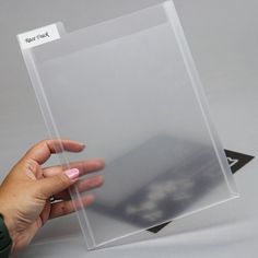 a hand holding a clear plastic sheet on top of a table