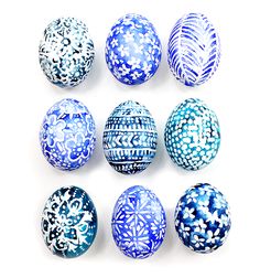 six blue and white decorated eggs on a white surface