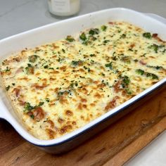 a casserole dish with cheese and broccoli in it on a cutting board