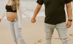 a man and woman holding hands while walking on the beach