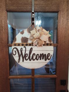 a welcome sign hanging on the front door to a house with a cow print bow