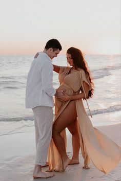 a man standing next to a woman on top of a beach