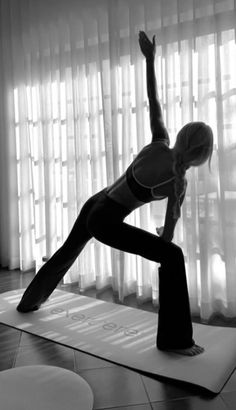 a woman is doing yoga in front of the window