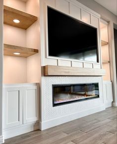 an empty living room with a large flat screen tv mounted above the fireplace and built - in shelving