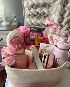 a pink basket filled with personal care items on top of a white table next to a bed