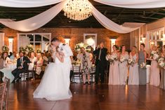 a bride and groom are kissing in front of their wedding party at the reception hall