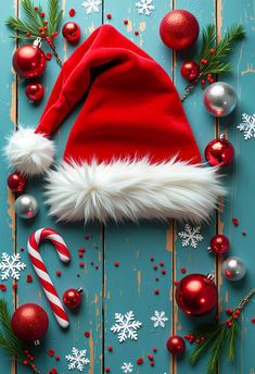 a red santa hat sitting on top of a wooden table next to christmas ornaments and candy cane