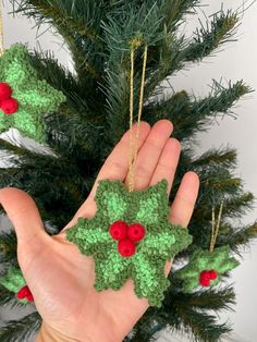 someone is holding up some crocheted ornaments in front of a christmas ornament