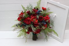 a bouquet of red flowers and greenery sits in front of a white door frame