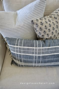 some pillows are sitting on the back of a couch with blue and white striped fabric